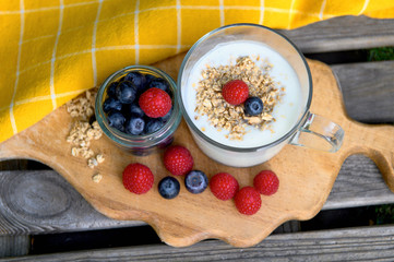 Eating a healthy breakfast. Yogurt, granola, chia seeds, fresh and dry fruits, blueberries, raspberries in a transparent. Clean food, diet, detox, vegetarian food concept.