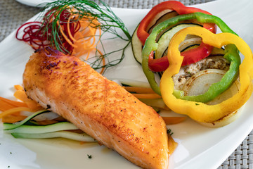 Salmon filet with vegetables on  a white plate