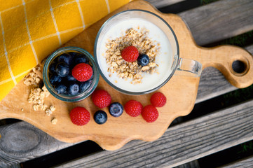 Eating a healthy breakfast. Yogurt, granola, chia seeds, fresh and dry fruits, blueberries, raspberries in a transparent. Clean food, diet, detox, vegetarian food concept.