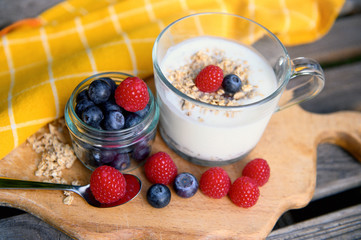 Eating a healthy breakfast. Yogurt, granola, chia seeds, fresh and dry fruits, blueberries, raspberries in a transparent. Clean food, diet, detox, vegetarian food concept.