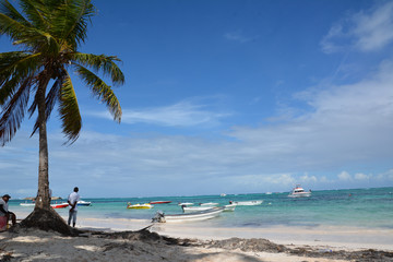 Fototapeta na wymiar Bavaro, Dominican Republic - January 17, 2018. Beach, white sand, palm trees and boats in the ocean and blue sky.