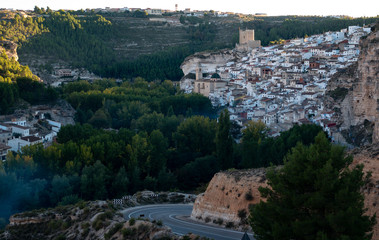Pueblo medieval mediterráneo de casas blanca en ladera de montaña junto a bosque
