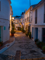 Fototapeta na wymiar Calle española de Andalucía de la costa del sol amaneciendo llena de macetas y fachadas de cla
