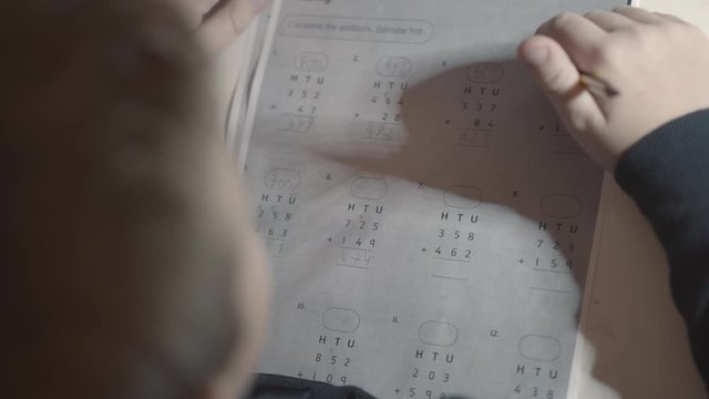 Schoolboy doing the tasks in Maths at home. He trying to concentrate and think over the sums