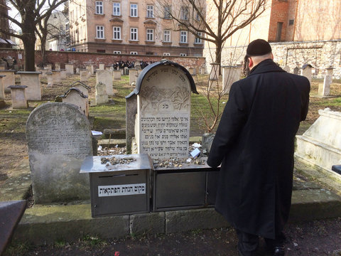 Un hombre reza ante una tumba del cementerio jud&iacute;o de Remuh en Cracovia, Polonia