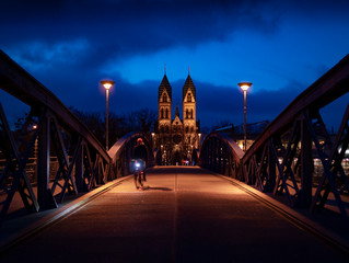 Obraz premium bicicleta cruzando puente por la noche azulada e iglesia al fondo
