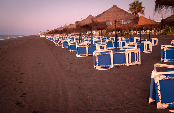 hilera de hamacas, tumbonas y sombrillas en playa desierta al amanecer