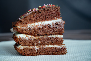 Chocolate Cake. Piece of Cake on a Plate. Sweet food. Sweet dessert. Black background. Close up. On a white stand