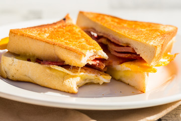 Toasted egg and bacon sandwich outdoors cut in half