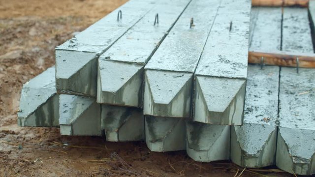 Concrete piles laying on the ground at the construction site. It is raining.