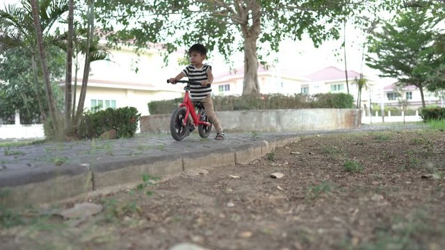 The boy trained to play a balance bike with her older sister tasing care of the garden