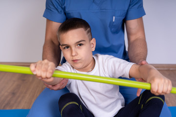 Physical Therapist doing exercises with teenage boy, with a stick.