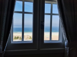 Window with View onto Enticing Empty Beach with Chairs on Sunny Day at Ocean