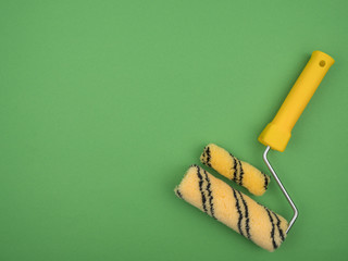 Paint rollers of different sizes on green background.