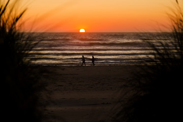 Oregon coast beach with a magnificent sunset and people taking a stroll.