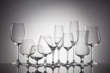 Empty clear glassware. Set of glasses for different alcoholic drinks and cocktails on dark gray...