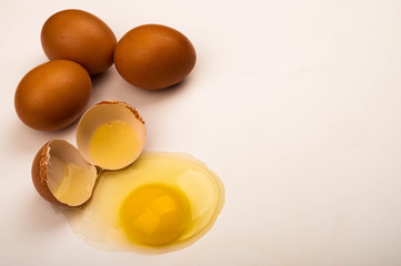 A broken chicken egg and scattered eggs on a white background. Close up.