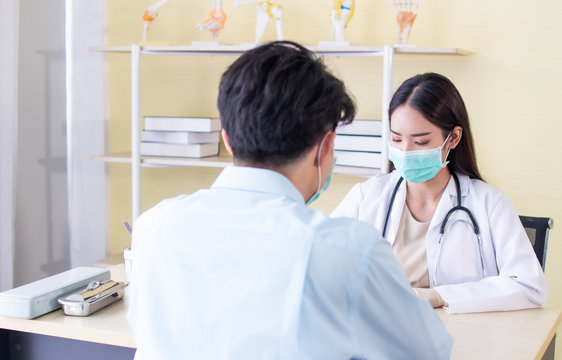 Selective focus. Asian doctors wearing surgical masks. Wearing doctor gown protective suit and stethoscope Consulting with patients. Blurred image rear view patient foreground
