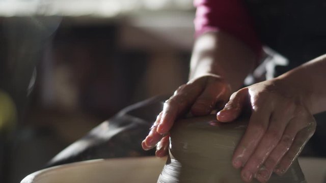 hands of the potter formed pitcher on a potter's wheel