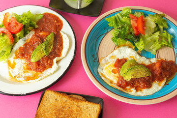 Huevos, recién horneados con una salsa de tomate y una ensalada con aguacate, para una dieta keto o personas fit.