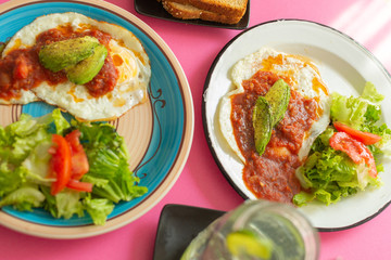 Huevos, recién horneados con una salsa de tomate y una ensalada con aguacate, para una dieta keto o personas fit.