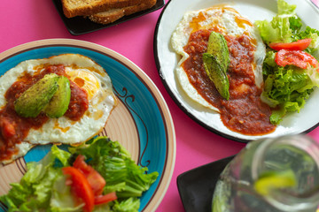 Huevos, recién horneados con una salsa de tomate y una ensalada con aguacate, para una dieta keto o personas fit.