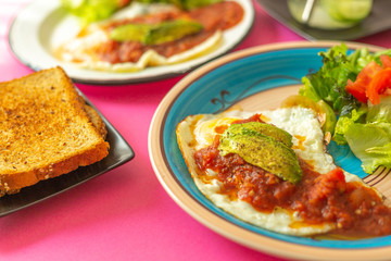 Huevos, recién horneados con una salsa de tomate y una ensalada con aguacate, para una dieta keto...