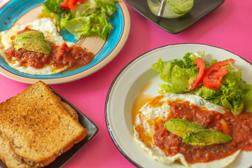 Huevos, recién horneados con una salsa de tomate y una ensalada con aguacate, para una dieta keto o personas fit.