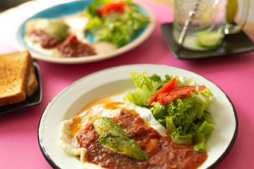 Huevos, recién horneados con una salsa de tomate y una ensalada con aguacate, para una dieta keto o personas fit.