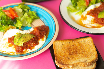 Huevos, recién horneados con una salsa de tomate y una ensalada con aguacate, para una dieta keto o personas fit.