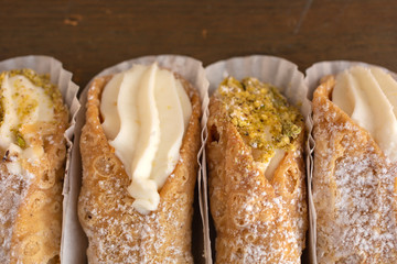 Top view of four delicious cannoli on wooden background