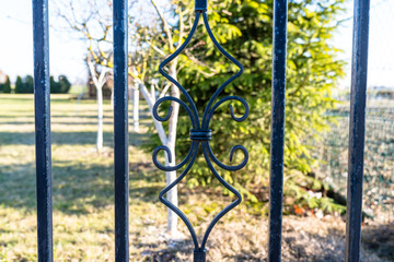 A decorative element of the wrought gate in black on the property of a single-family house.