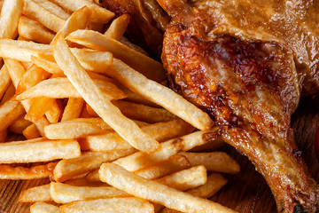 grilled chicken leg with french fries closeup
