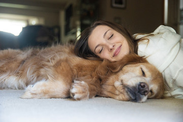 Teenage girl taking a nap on the floor with her golden retriever dog