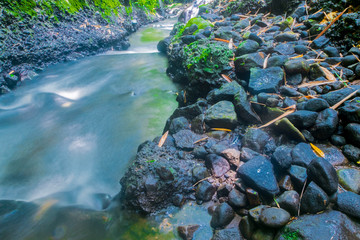 a collection of black stones located next to a very swift river flow