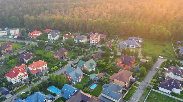 Aerial view of the residential neighborhood with the single-family homes near the forest in suburbs at sunset
