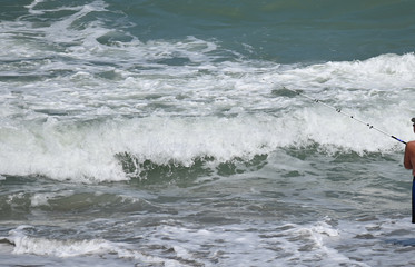 Man Fishing at Ocean Beach Surf with Social Distancing for Coronavirus Covid-19