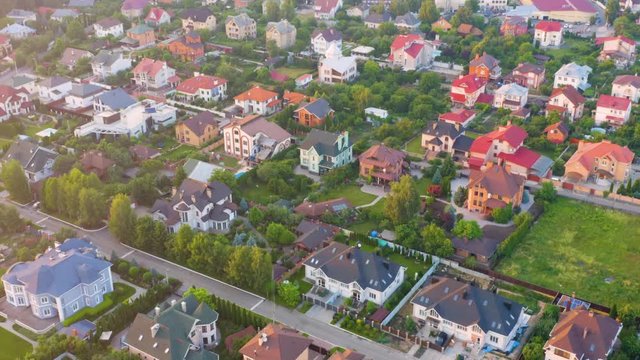 Aerial view of the residential neighborhood with the single-family homes near the forest in suburbs at sunset