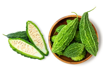 Closeup fresh bitter gourd ( cucumber, Momordica Charantia) in wooden bowl isolated on white...