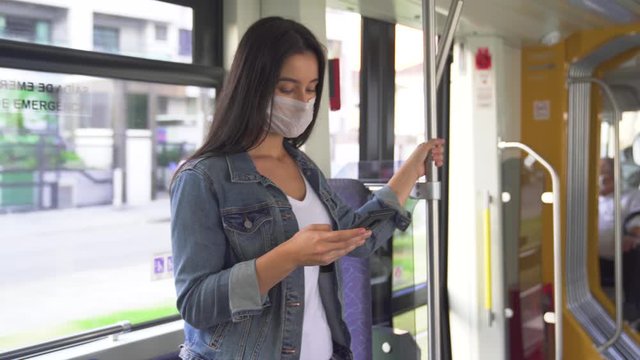 A young woman uses hand sanitizer liquid in a subway car, pandemic coronavirus concept
