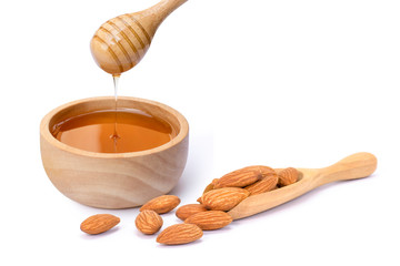Closeup almond nuts in wooden scoop and pure golden honey in wooden bowl isolated on white background.