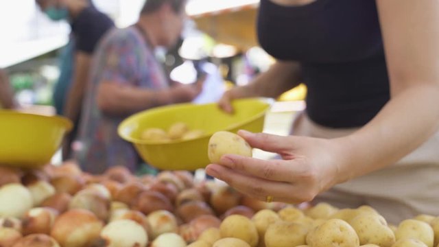 Young woman in mask picking potatoes at grocery store during pandemic
