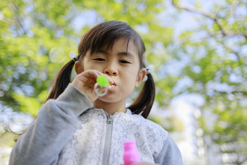 緑の中でシャボン玉で遊ぶ幼児(5歳児)