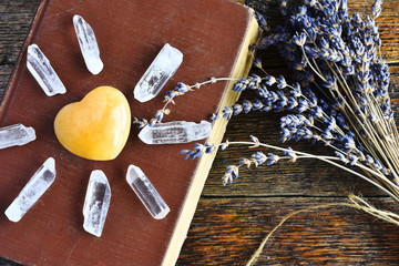 A top view image of a yellow heart shaped calcite crystal on an old book with dried lavender...