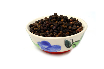 Black pepper in yellow bowl isolated on white background