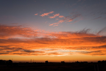 Sunset landscape, an orange bright sky and small silhouettes on the horizon