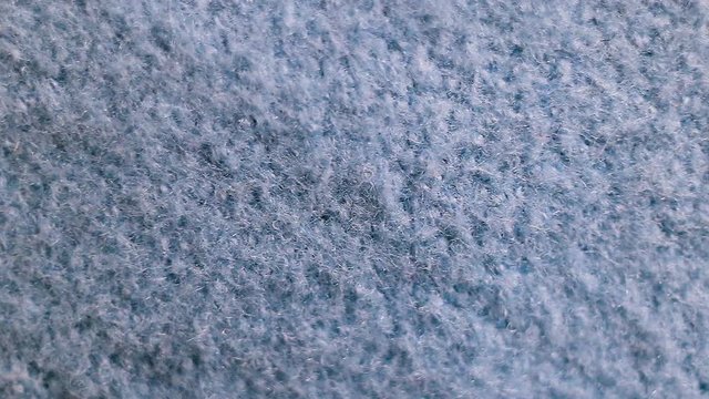 Fluffy dense fleece blue unnatural fabric made of microfiber fiber. Real time, camera movement, loose texture, background, extreme close-up