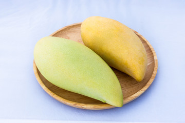 Closeup of Barracuda Mango Fresh and golden yellow on wood tray and white background. Is a famous fruit of Thailand. Select focus