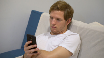 Smartphone and Social Media Addiction - Young Man Mindlessly Staring at Phone While Sitting on Couch