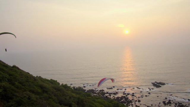 Paragliding in flight over the beach of Kalacha at sunset. Arambol. Goa, India.